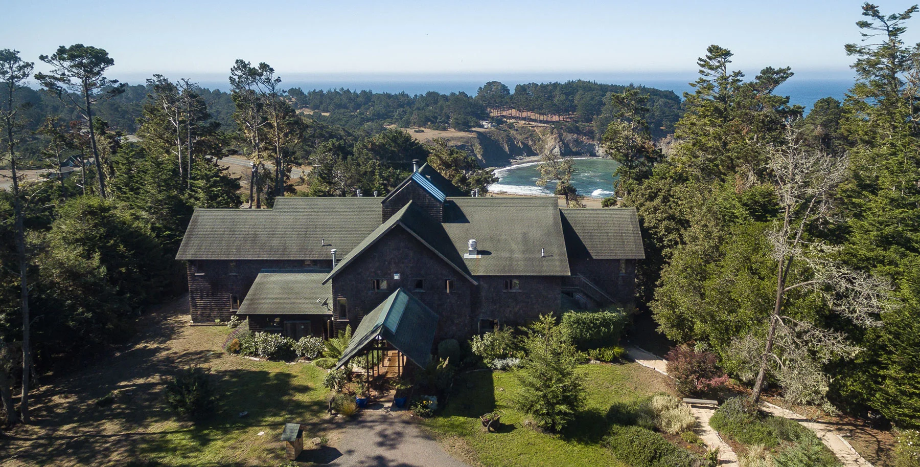 An aerial view of Brewery Gulch Inn sitting among trees with the Pacific Ocean in the distance.