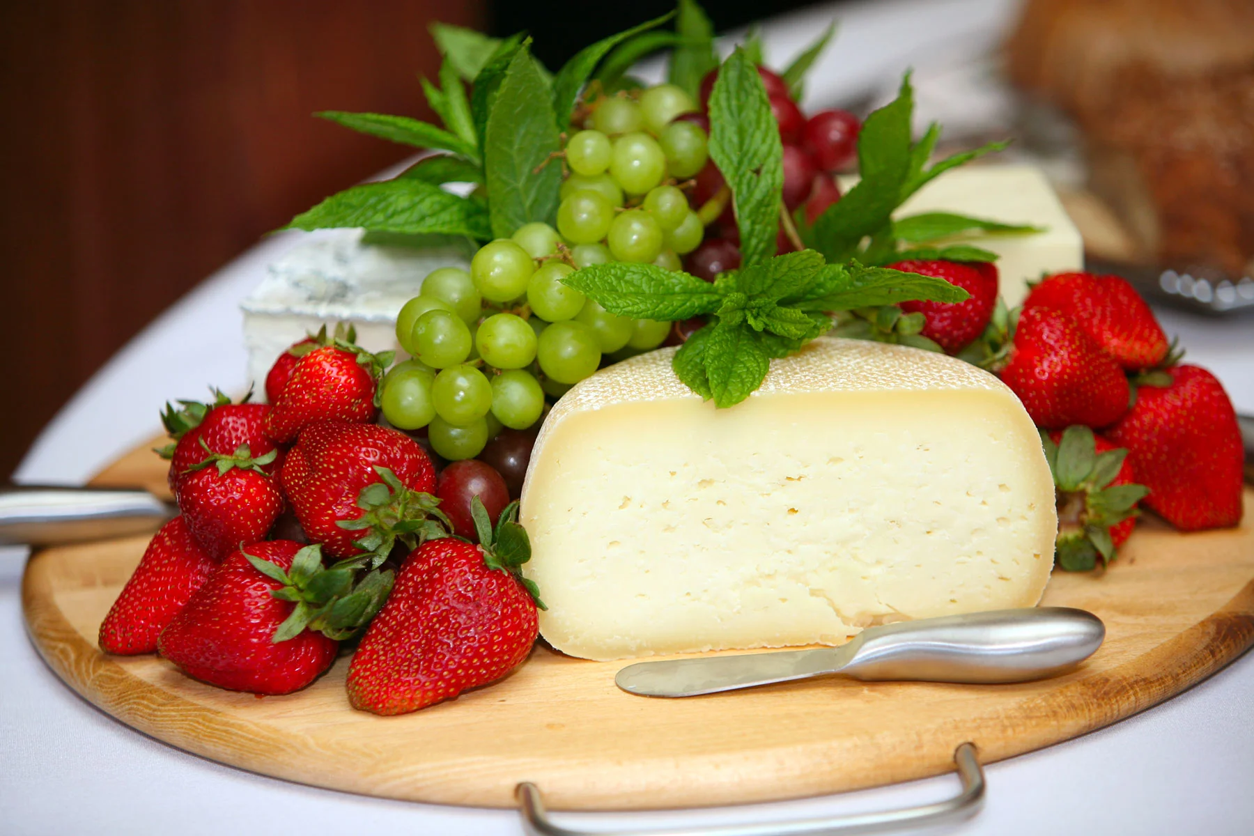 Cheese and fruit on a wooden board.