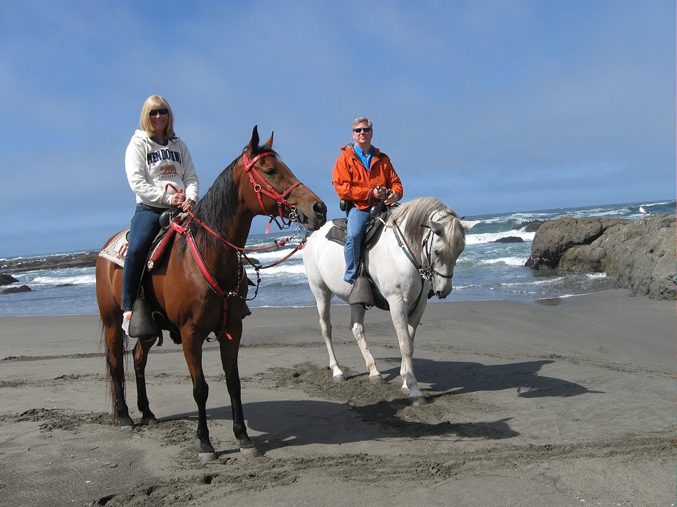A couple on horseback on a beach north of Mendocino, California.