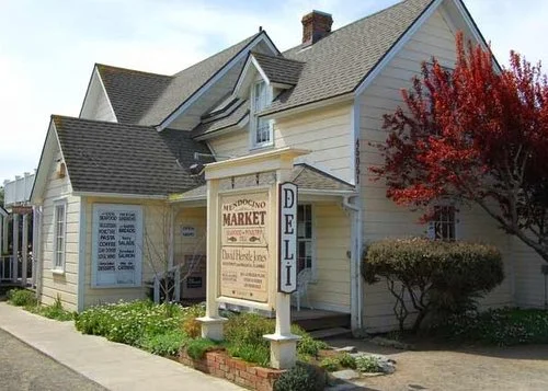 The Mendocino Market is located in a small yellow building with peaked roofs in Mendocino, California.