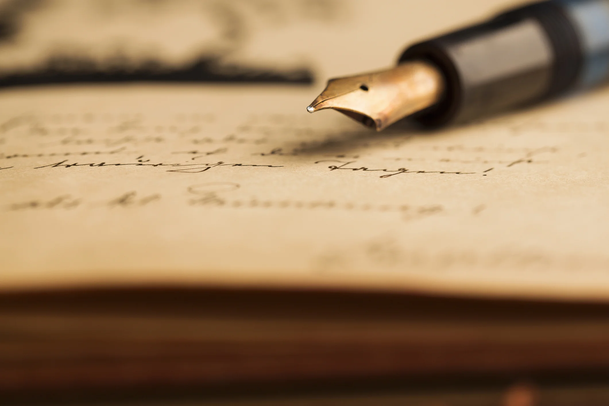 The tip of an old fashioned pen atop of a lovely notecard.