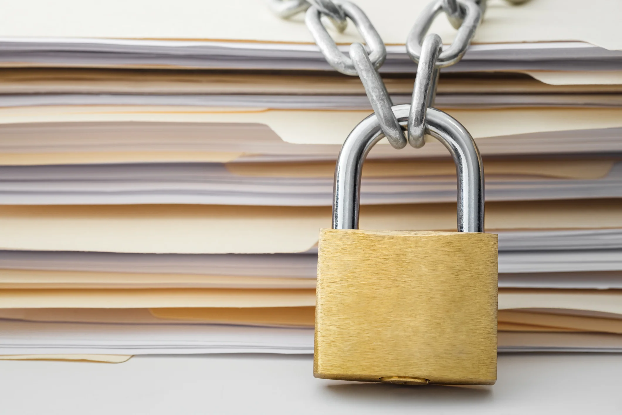 A padlock and chain on top of a stack of folders.