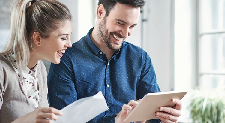 photo of smiling couple looking at iPad and papers