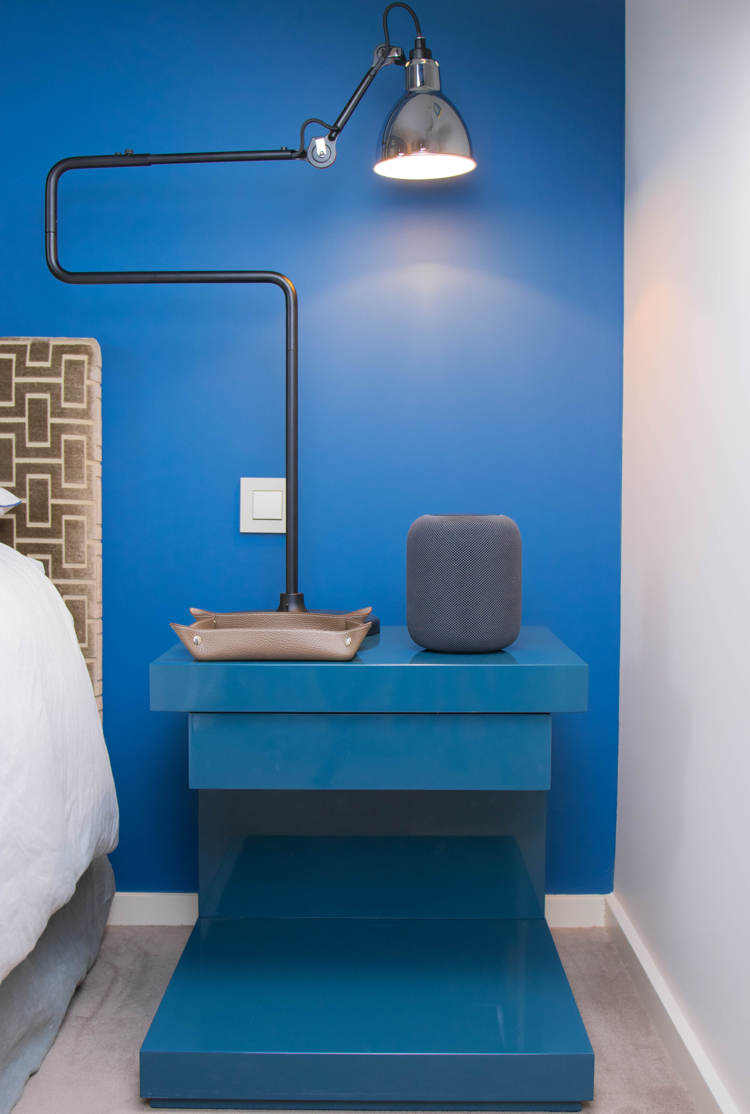 interior shot of a nightstand against a blue wall with a lamp
