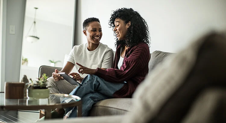 smiling couple seated on couch looking at iPad