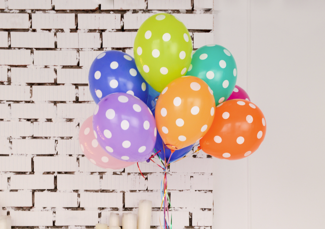 bunch of polka dot balloons in front of brick wall