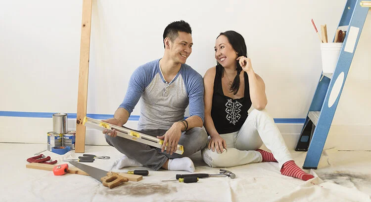 happy couple surrounded by tools sitting on floor