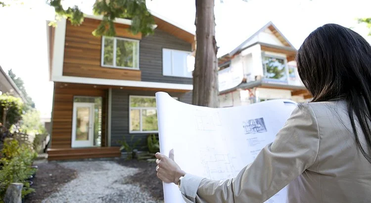 woman with house plans looking at house