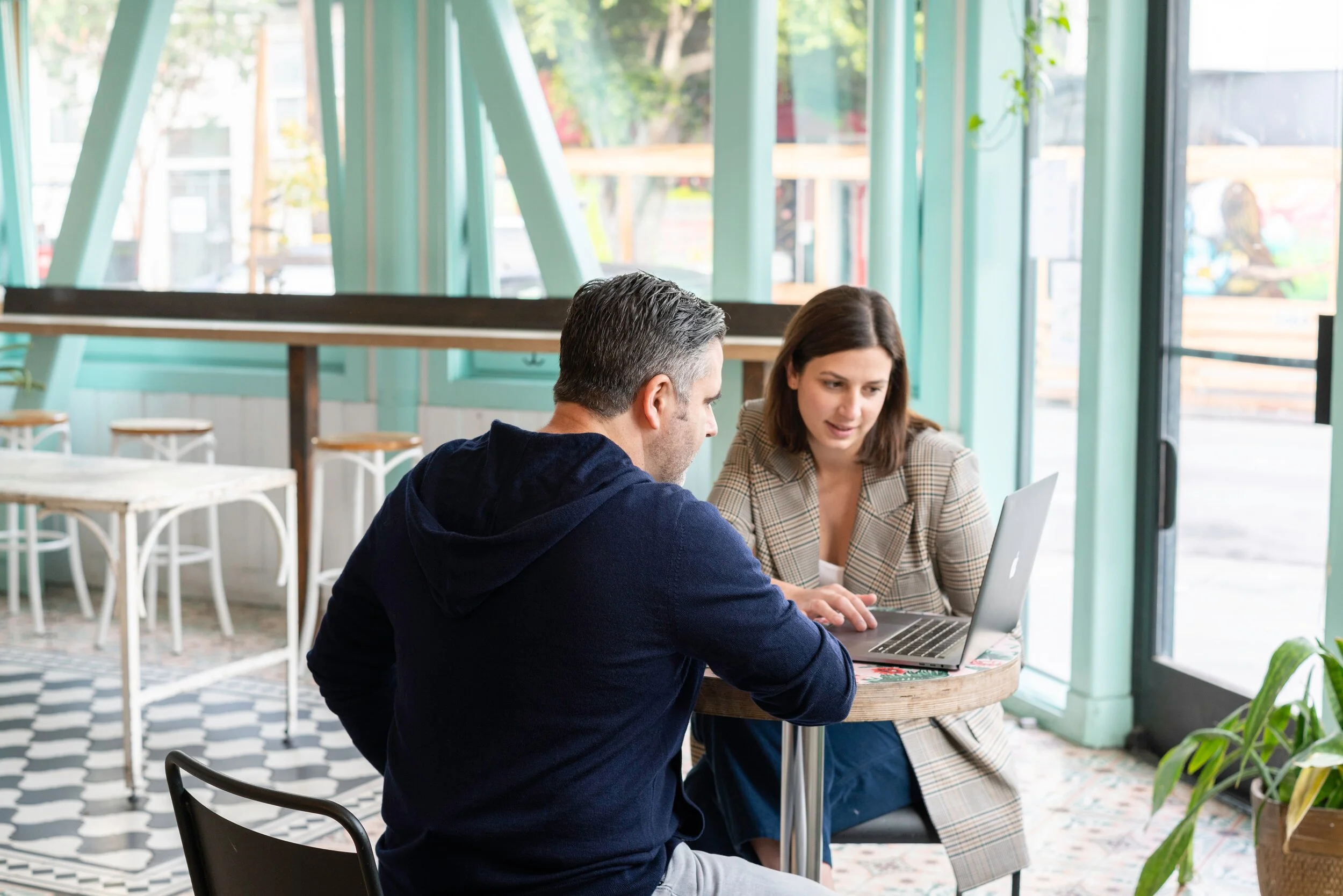 two people looking at a laptop in a coffeeshop