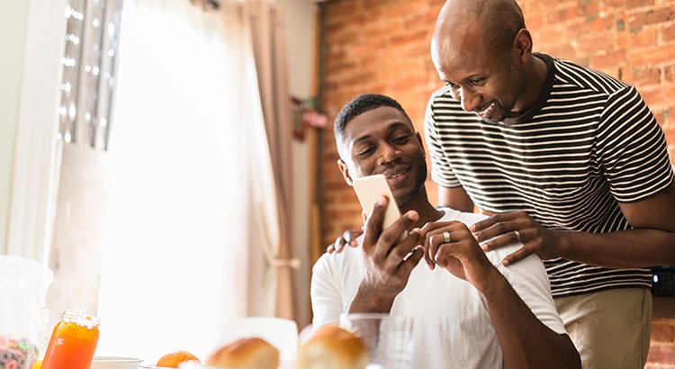 father and son looking at smartphone inside their home smiling