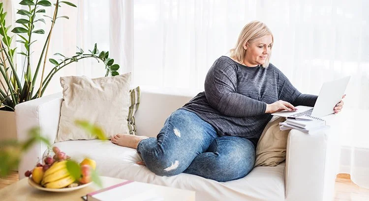 woman sitting on couch looking at computer