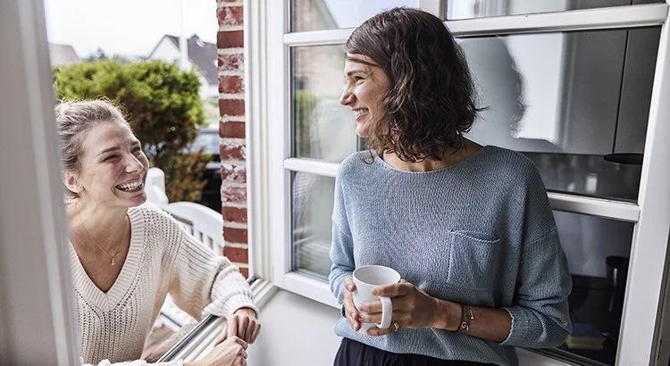 two women talking with coffee smiling