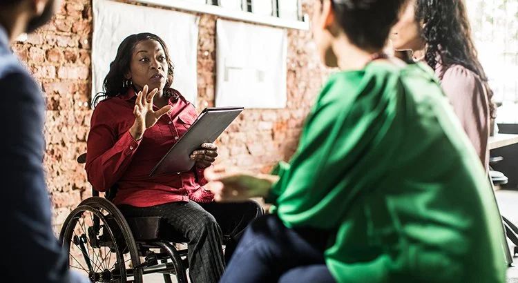 woman with legal pad taking to a group