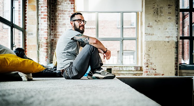 man sitting on the floor in. a loft style condo