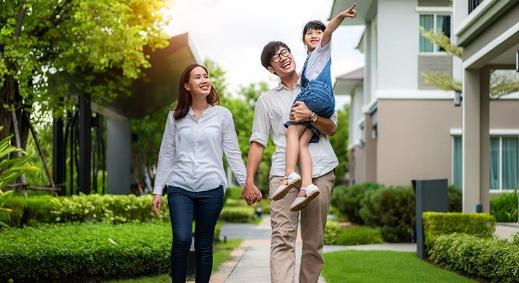 man woman and child walking down a sidewalk near homes