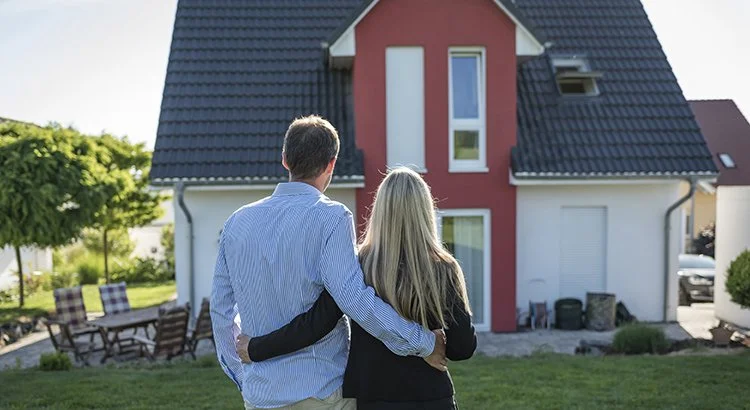 man and woman standing outside in front of a home