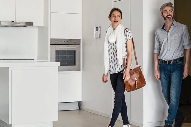 man and woman looking happy as they walk through a condo