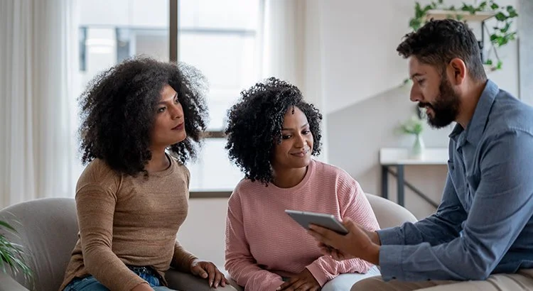 three people looking at an iPad inside a modern home