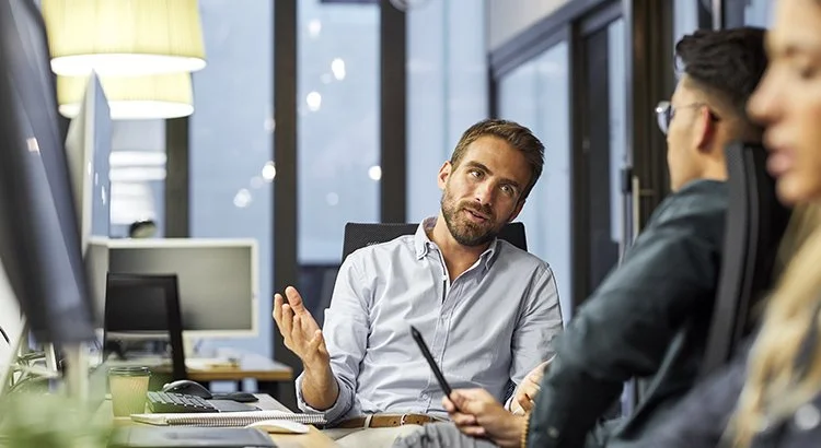 man sitting in office talking to others