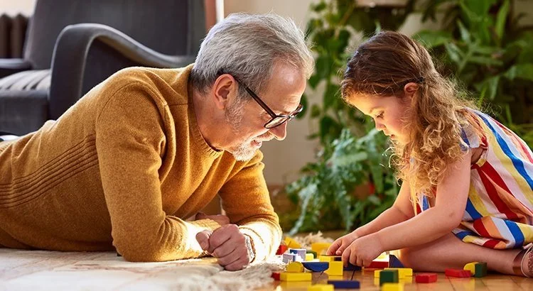 older man playing legos with a young girl in a living room
