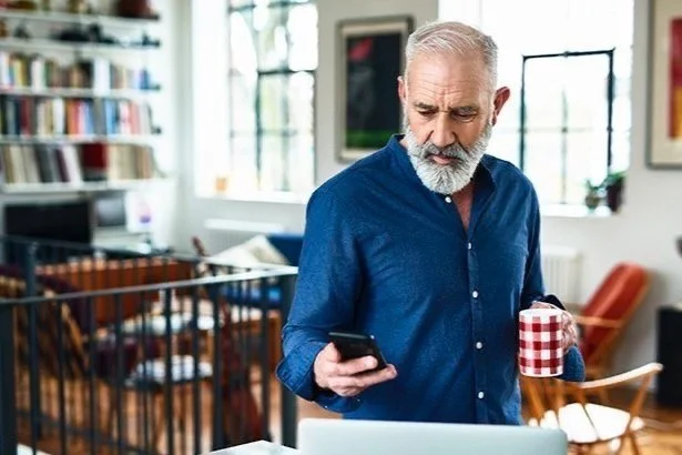 senior man in modern loft looking at phone