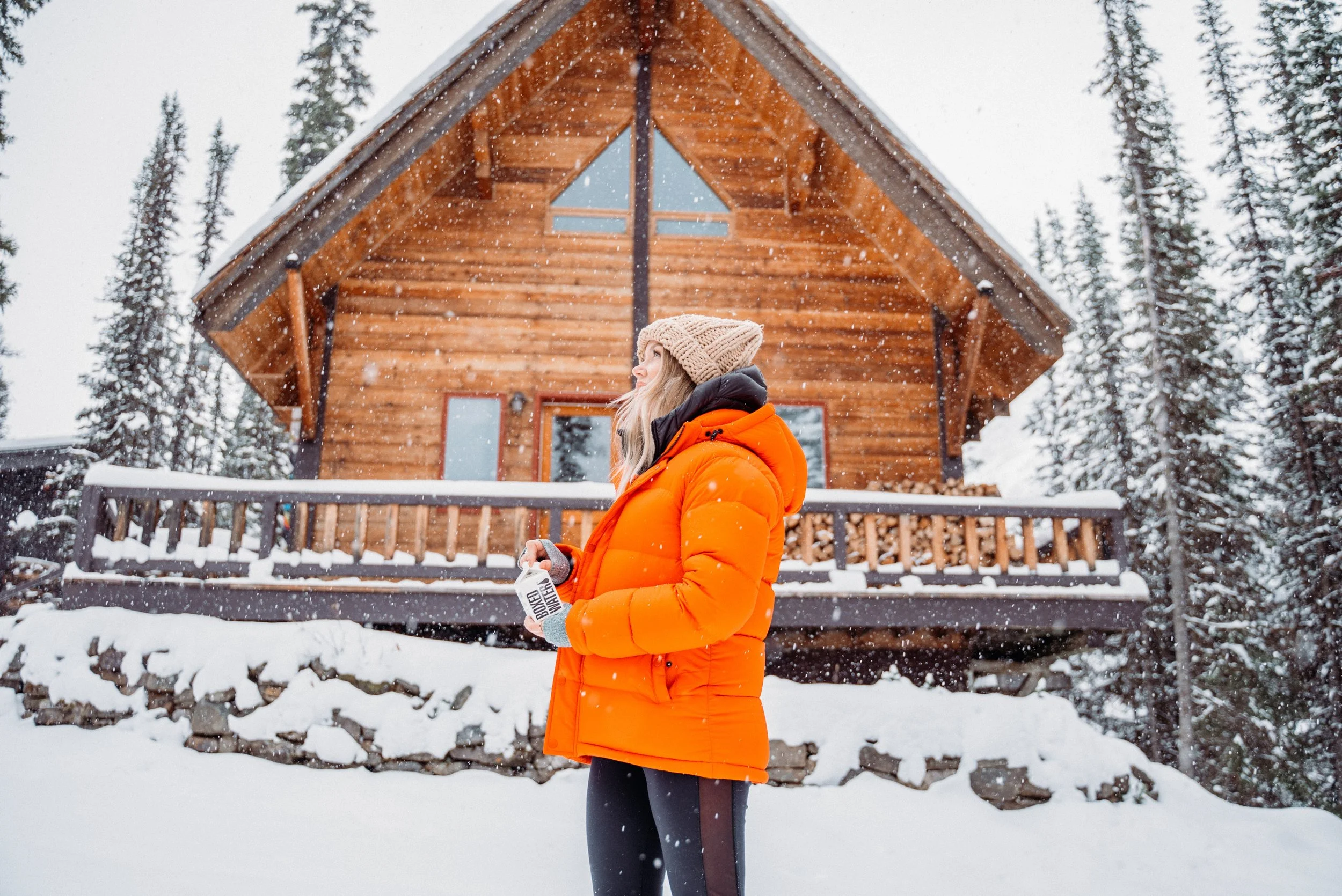 woman standing outside a cabin house in winter