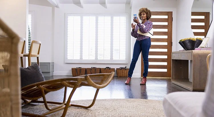 woman standing in living room holding  phone