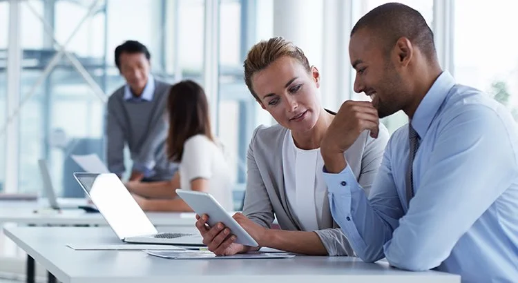 woman and man in office looking at iPad to research home loans
