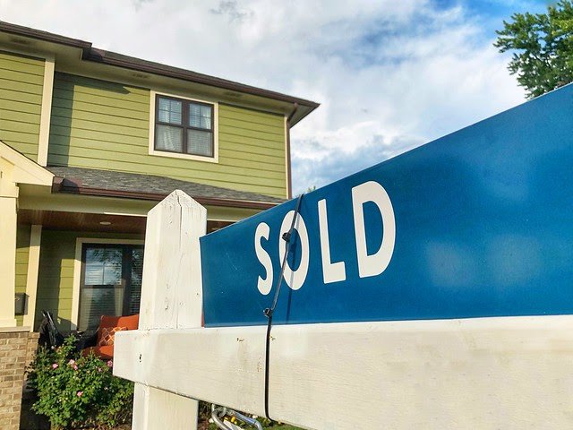real estate sold sing in front of a home
