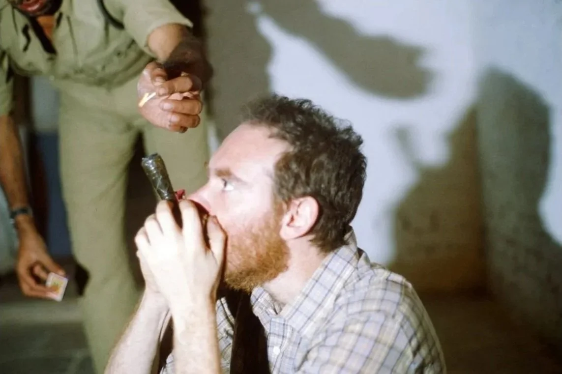 Ed Rosenthal smoking a chillum in India in 1981 as a police officer lights it, during a period when cannabis cultivation was legal and regulated.