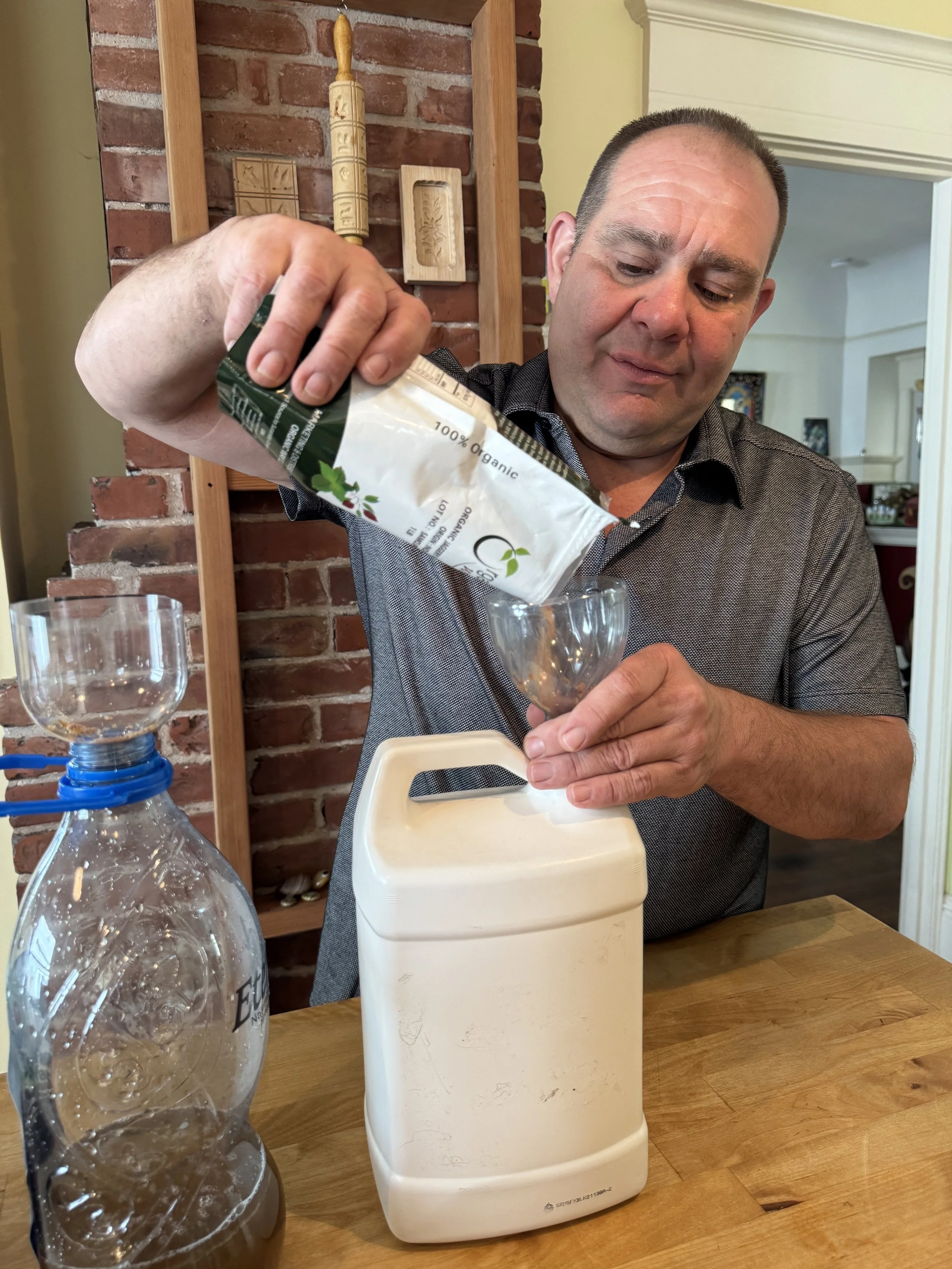 Frank from Purple Caper pouring unrefined organic sugar into a container while preparing a homemade carbohydrate loader for cannabis plants, with opaque bottles recommended for storage.