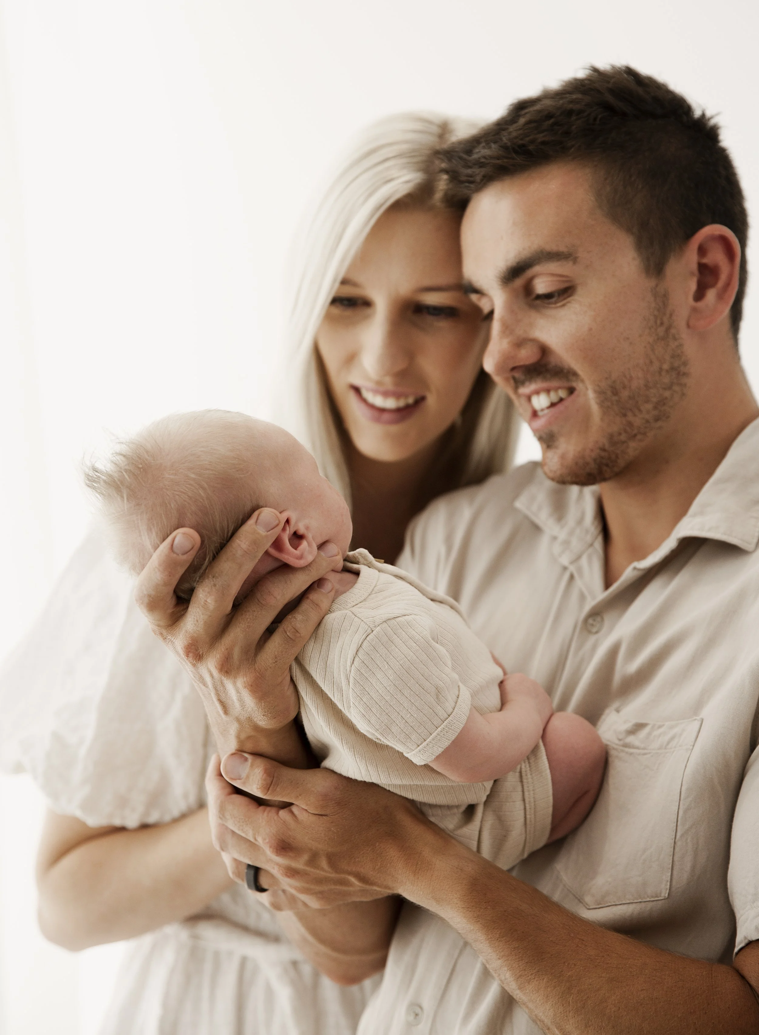 A couple holding and admiring their newborn baby together.