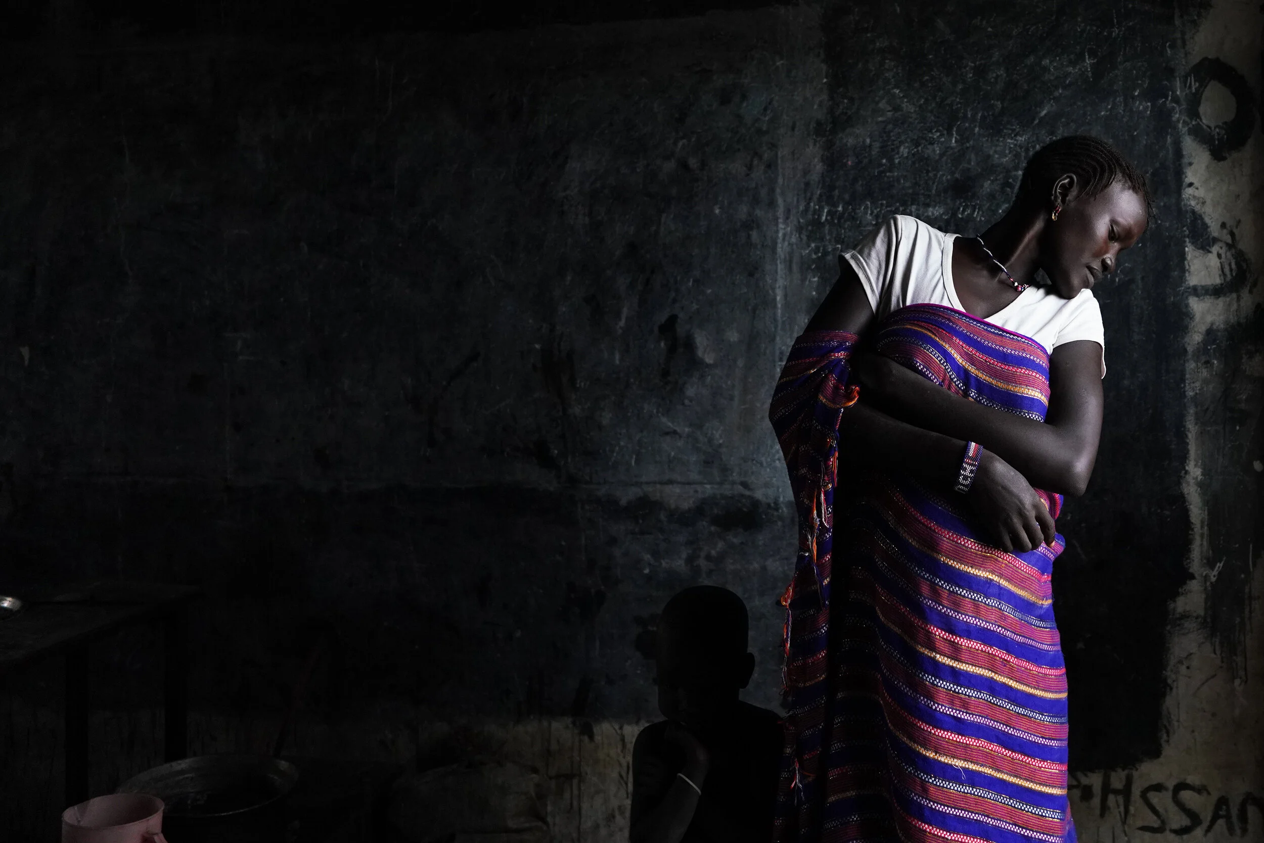  A woman displaced by the floods in Pibor, in 2019, who found refuge in a school is looking at her daughter who is hiding behind her.  