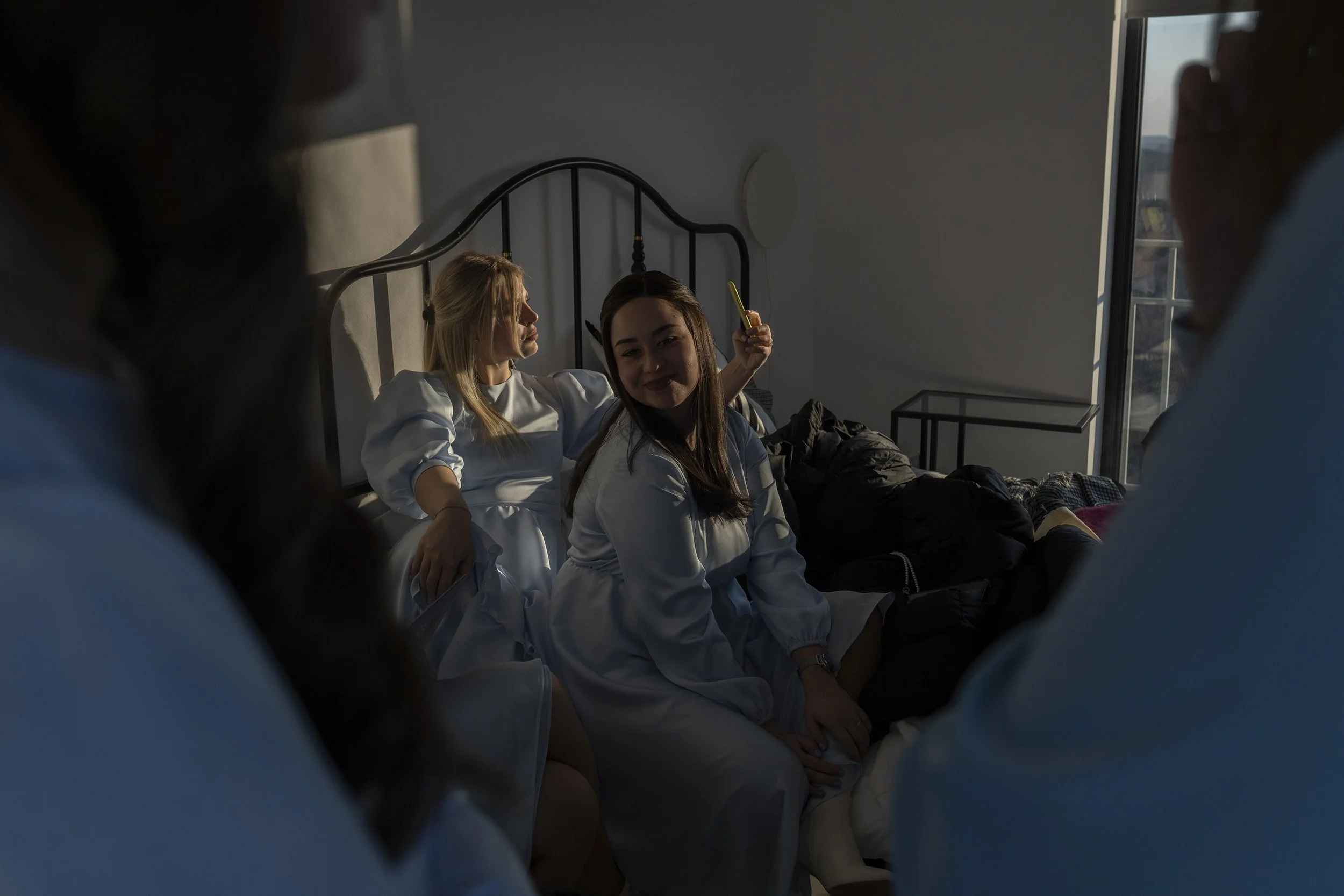  Bridesmaids rest on a bed during a photoshoot before a wedding. 