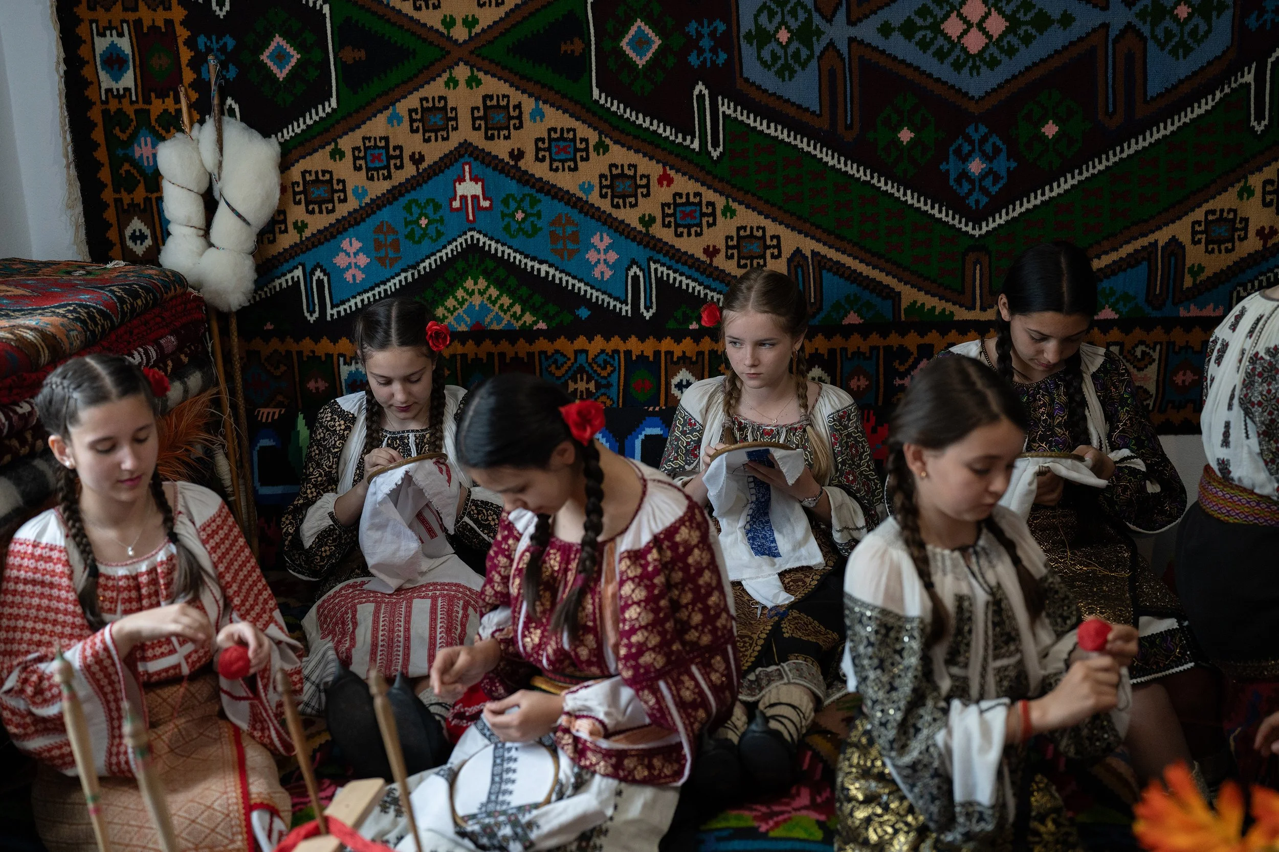  Girls from "Sezatoarea domnisancelor", wearing old traditional cloths which they usually wear for special events, embroider Romanian blouses, in Domnesti, Romania, in 2025.  