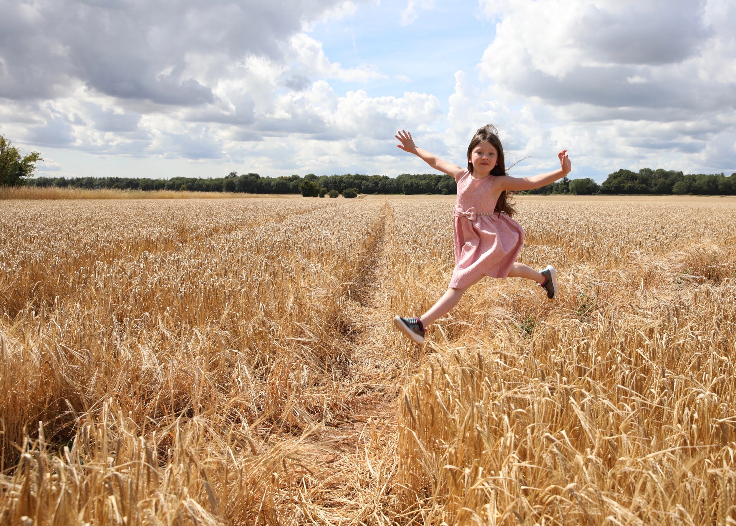 Girl jumping in barley field