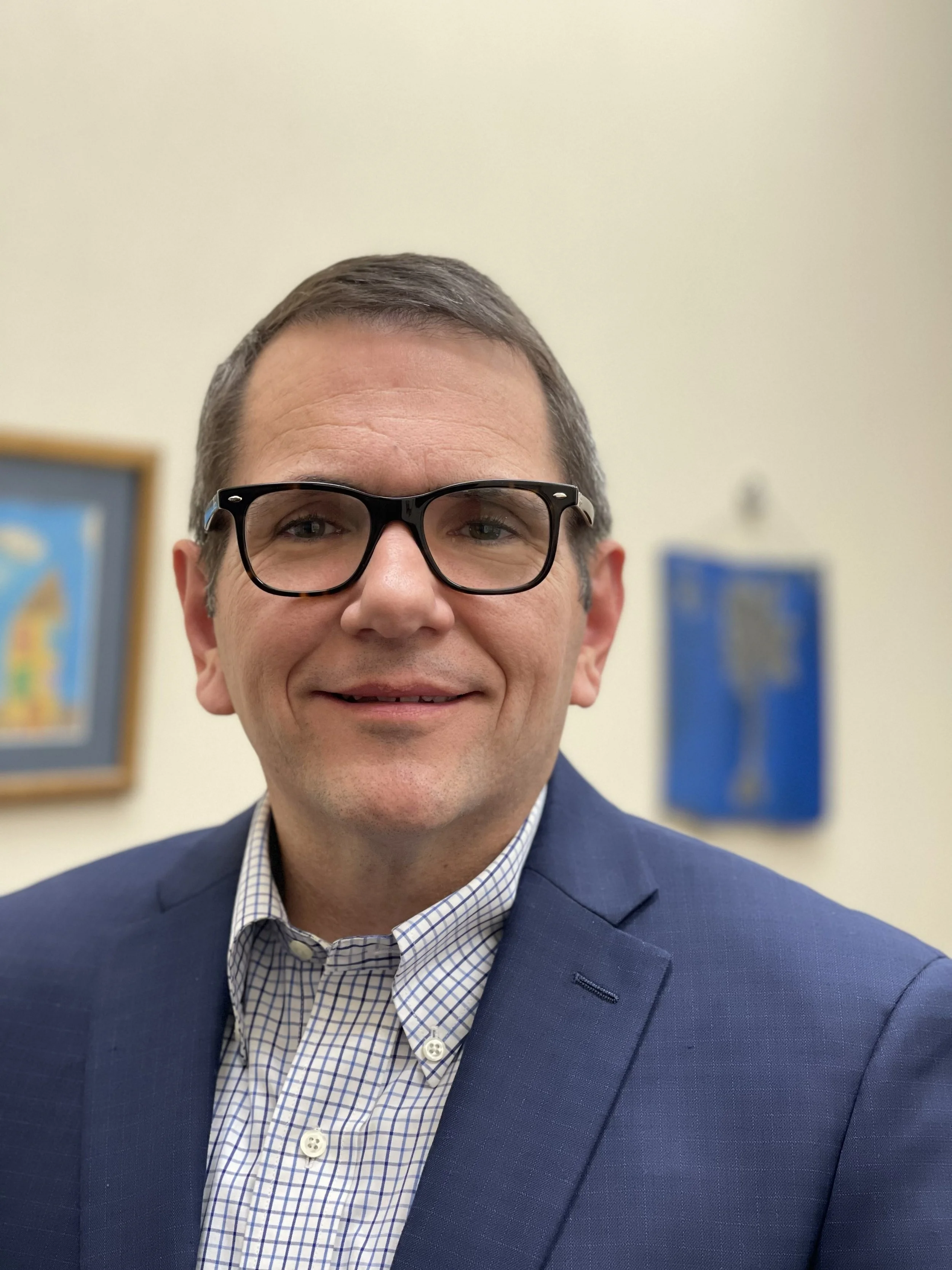 Sam, a white man with glasses in a blazer.