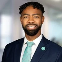 Dennard Small, a Black man with a beard wearing a suit.