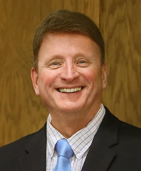 Dan, a white man with short brown hair in a suit.