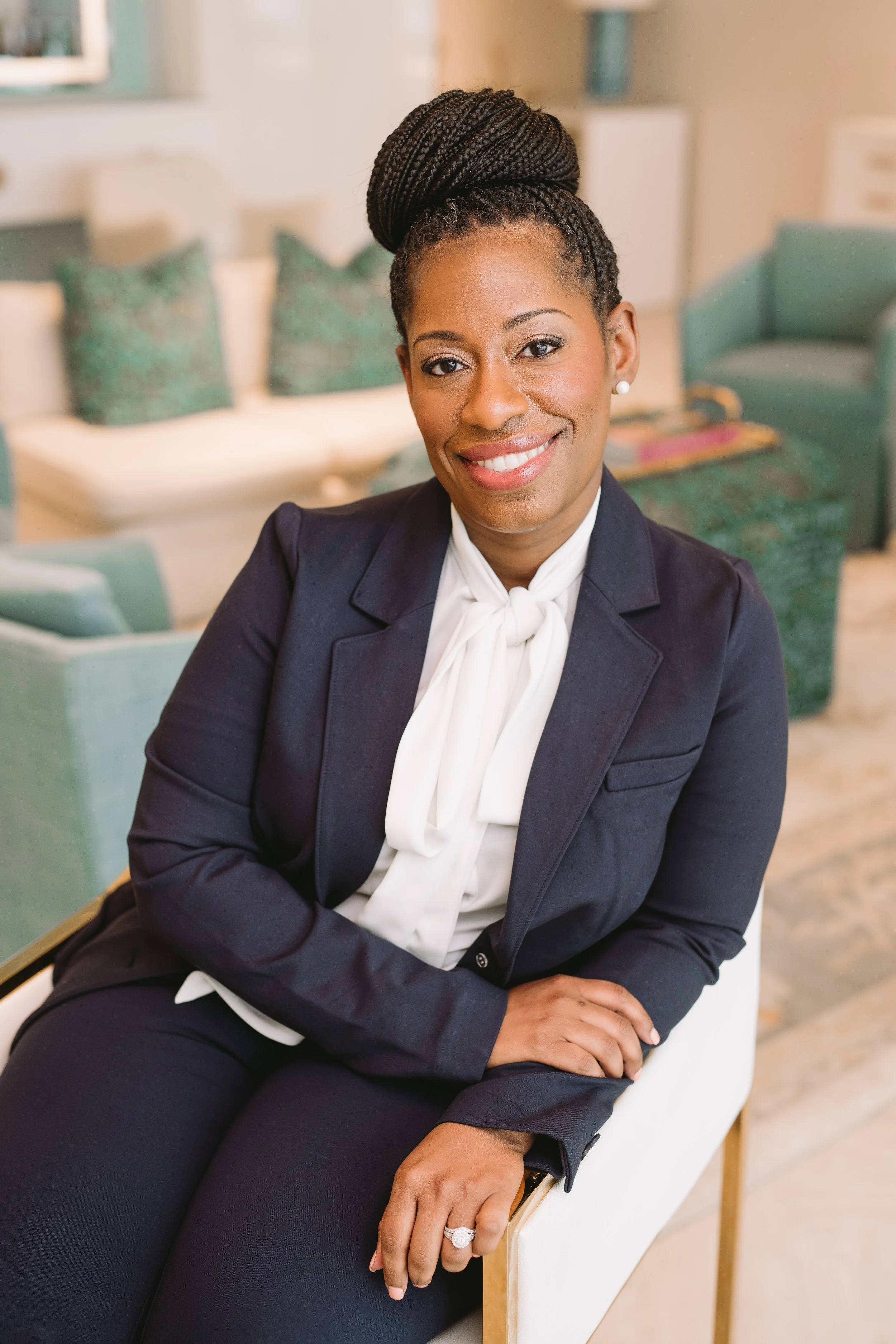 Olivia Scott, Black woman with braids in a bun wearing a suit.
