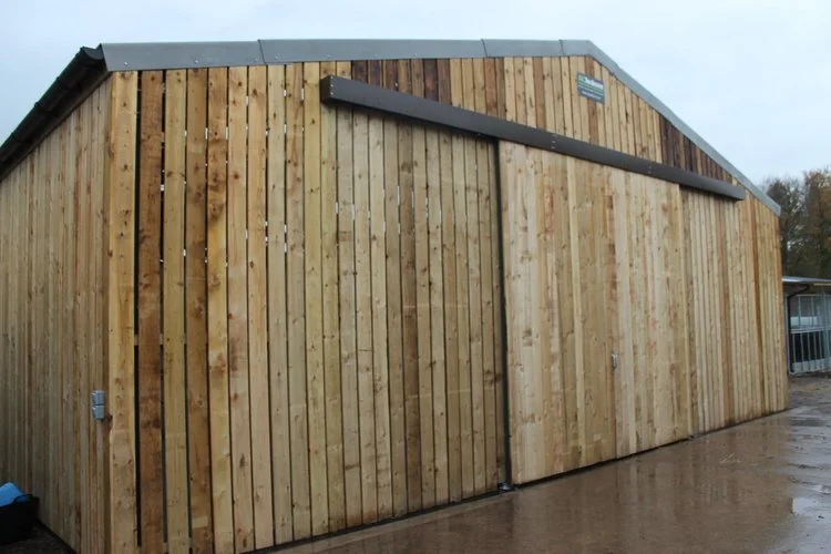 Large timber-clad agricultural barn with sliding wooden doors.jpeg