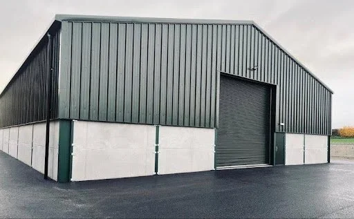 Green steel agricultural building with roller shutter door.