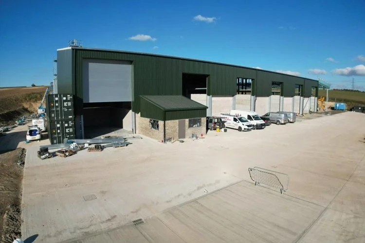 Large green steel grain storage warehouse with roller shutter entrance