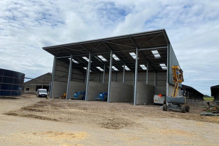 Steel-framed agricultural building under construction with construction equipment on site
