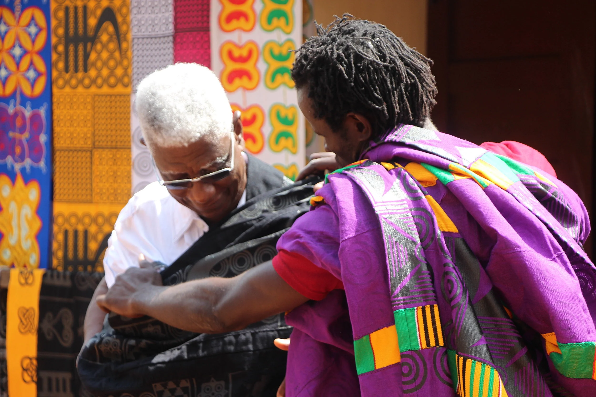 Peter Boakye demonstrates the art of wearing Adinkra cloth with El Anatsui. Every style of trying the cloth has a different meaning