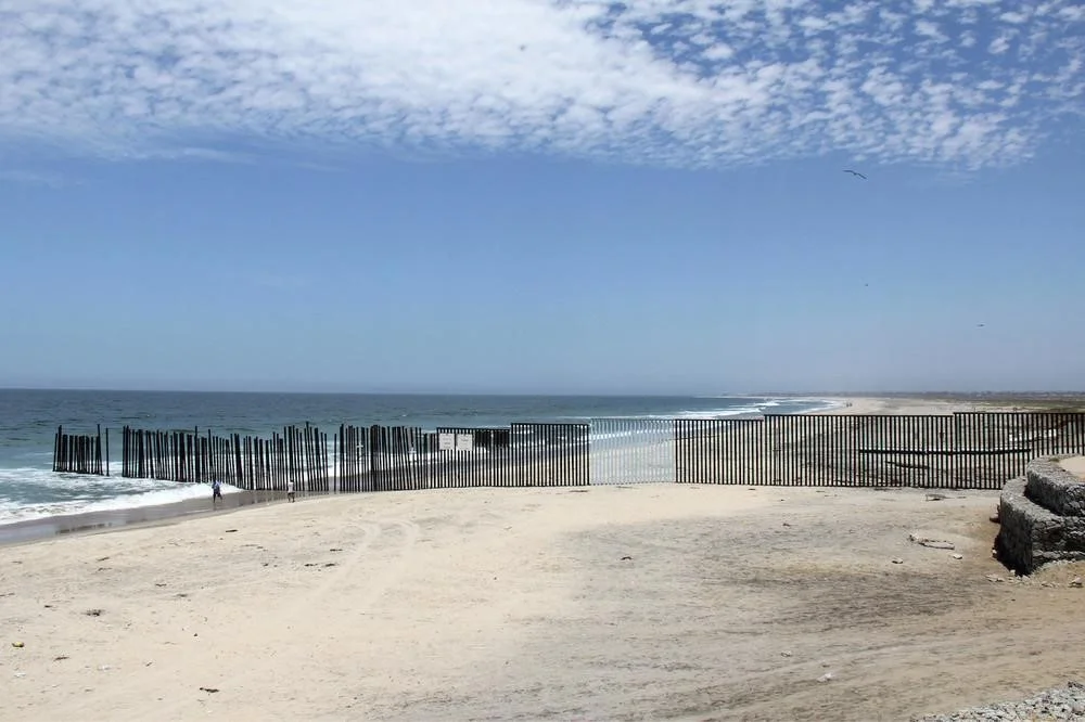 Part of the border fence that separates the United States from Mexico, where artist Ana Teresa Fernández has painted a section to match the sky to "erase" the fence. All photos courtesy of the artists
