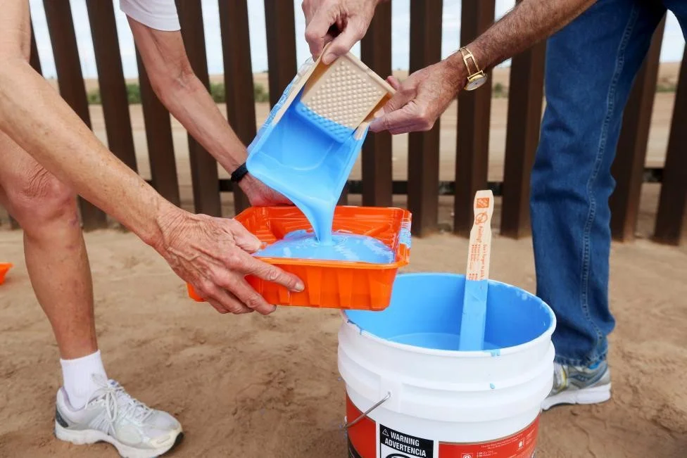 Genaro Fernandez (L) and Dan Watman prepare to paint the border fence in Mexicali, Mexico. REUTERS/Sandy Huffaker