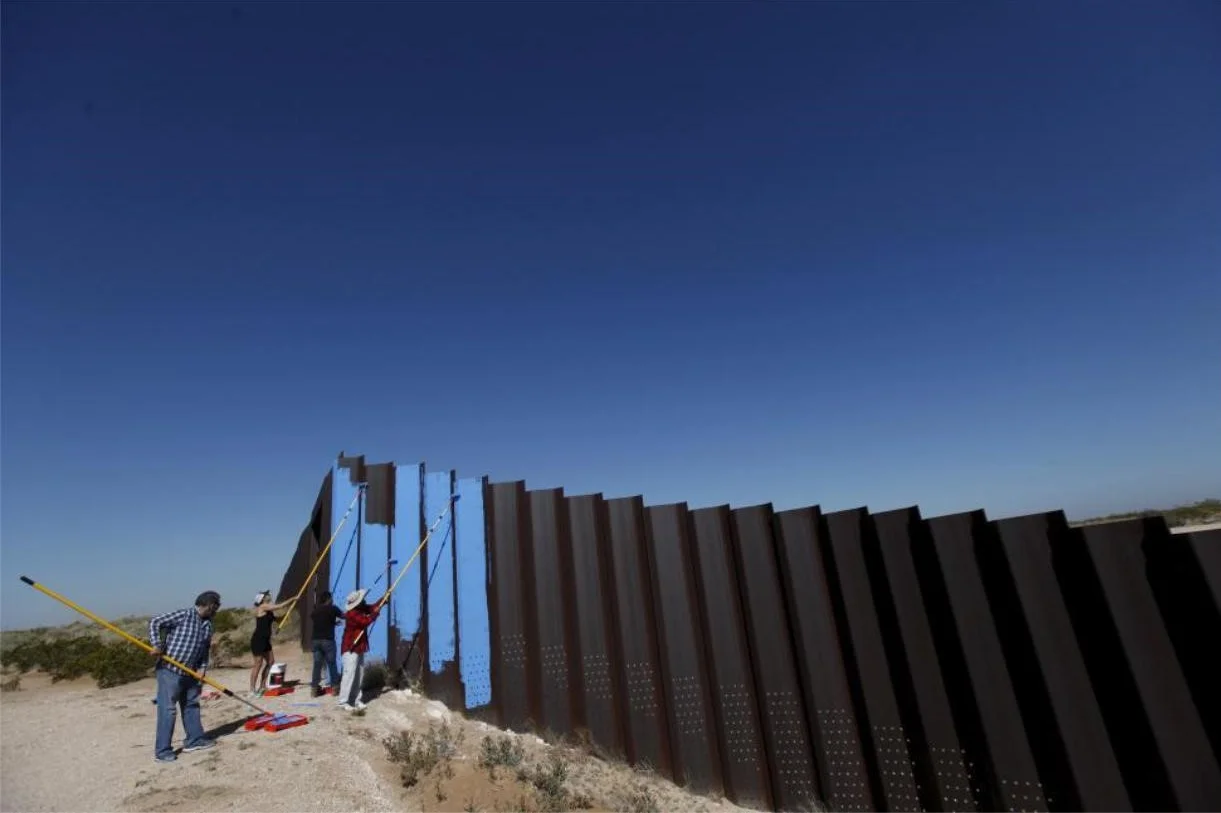 Artist Ana Teresa Fernandez (in black) and members of cultural organization "Border/Arte" paint the border fence in Ciudad Juarez, Mexico. REUTERS/Jose Luis Gonzalez