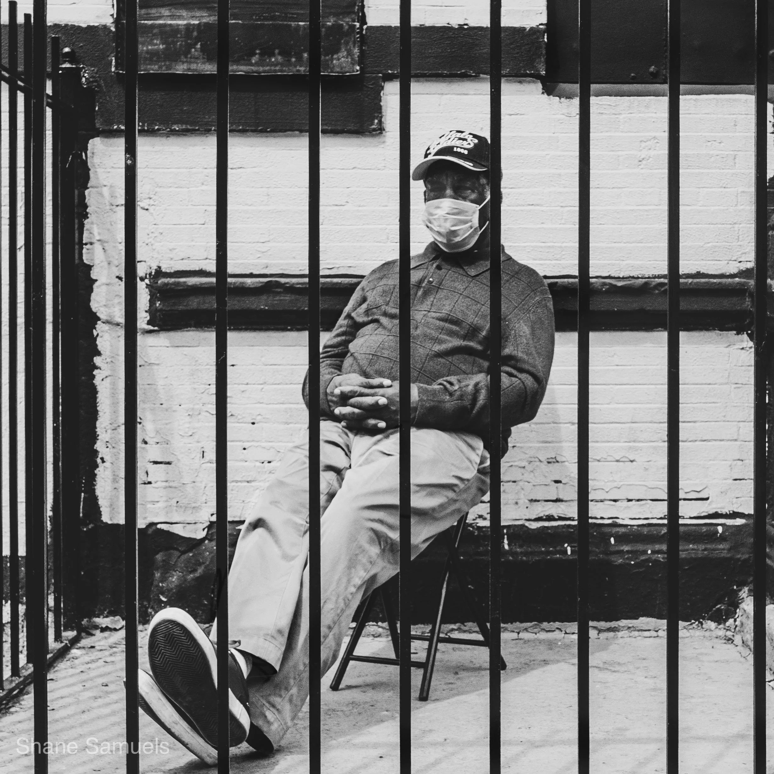 man sitting behind fence in Washington Heights NY