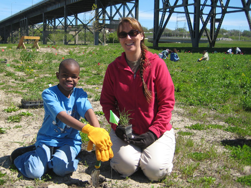 Jóvenes y adultos plantando un árbol en los terrenos del Centro Industrial de Menomonee Valley